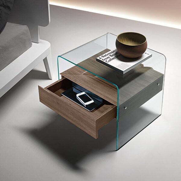 A minimalist bedside table composed of clear glass, which forms the sides and top of the table, and light brown wood.