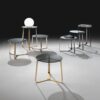 A collection of modern coffee tables and side tables featuring a circular glass top with sleek gold and black metal legs.